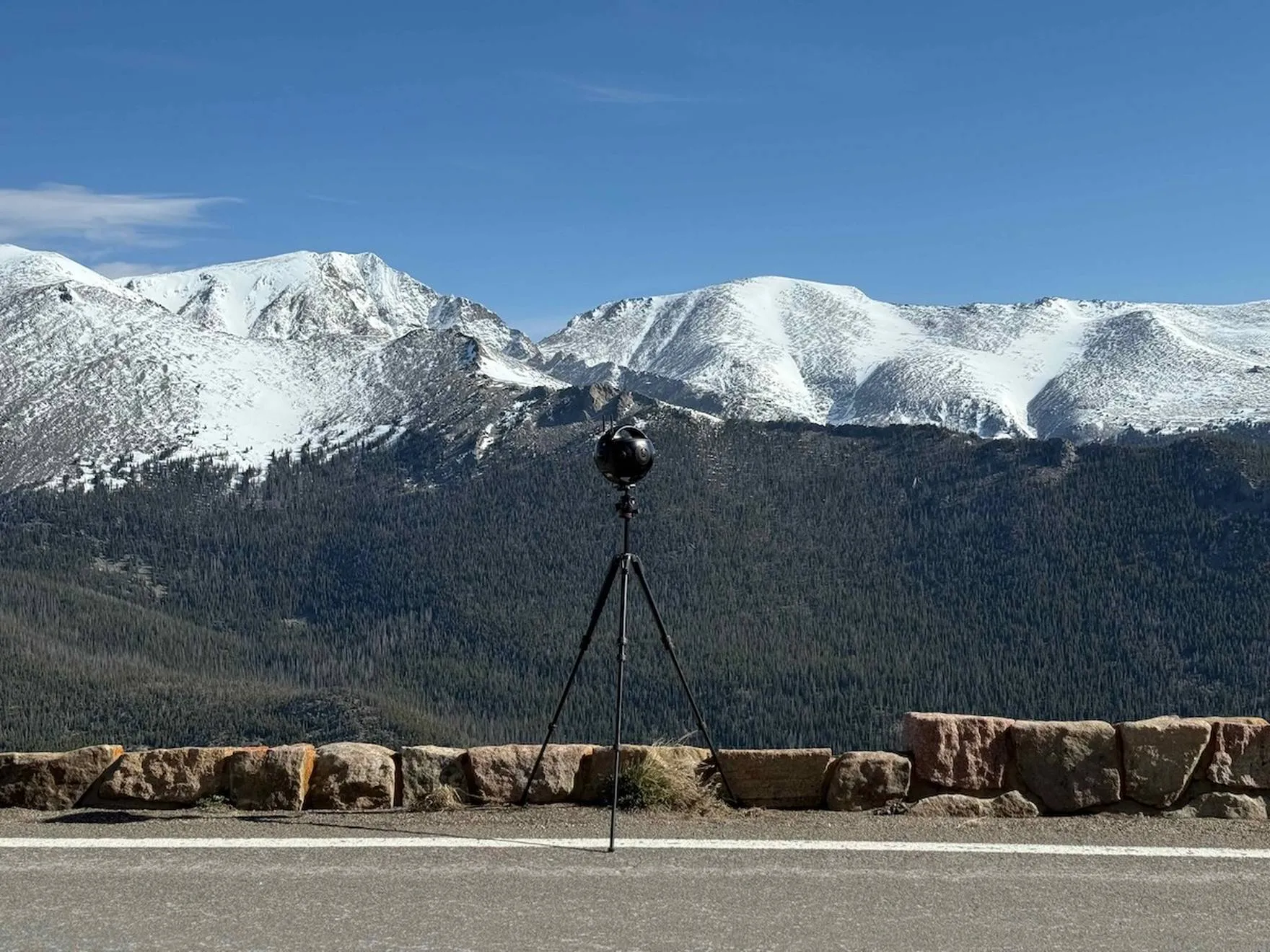 A 360-degree capture camera on a tripod before snow-capped Colorado peaks